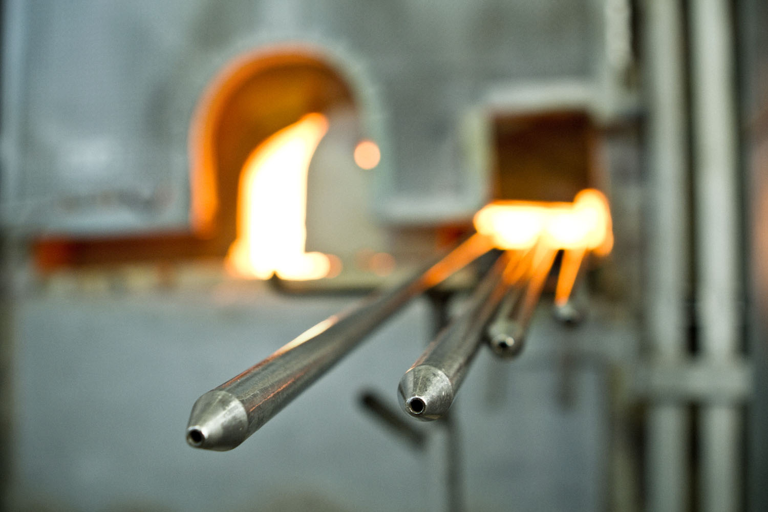 FLUID, WonderGlass. Design by Nao Tamura. | Blowpipes at the furnace mouth, waiting. FLUID begins here—a breath into molten glass.